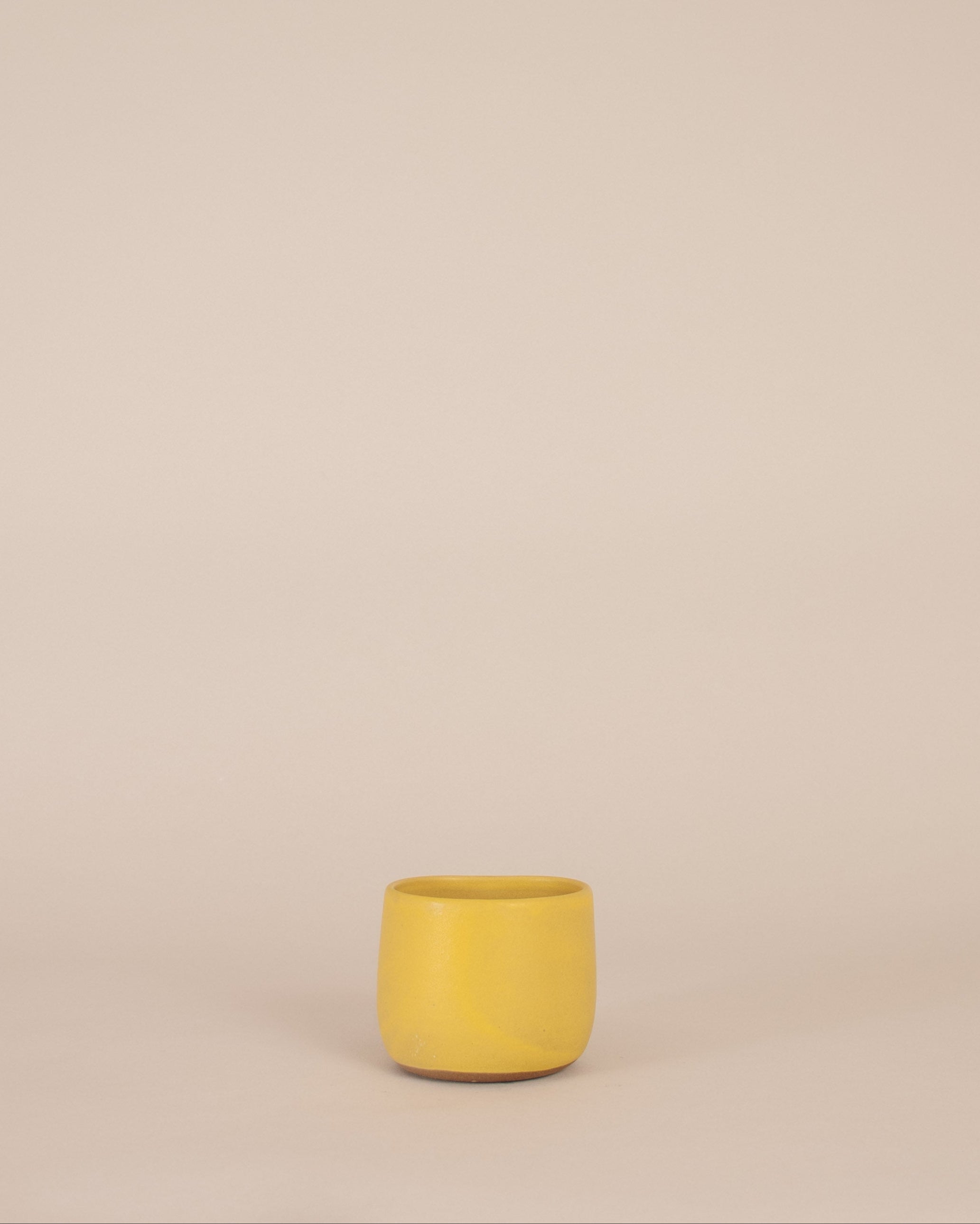 Yellow ceramic cup on a beige background